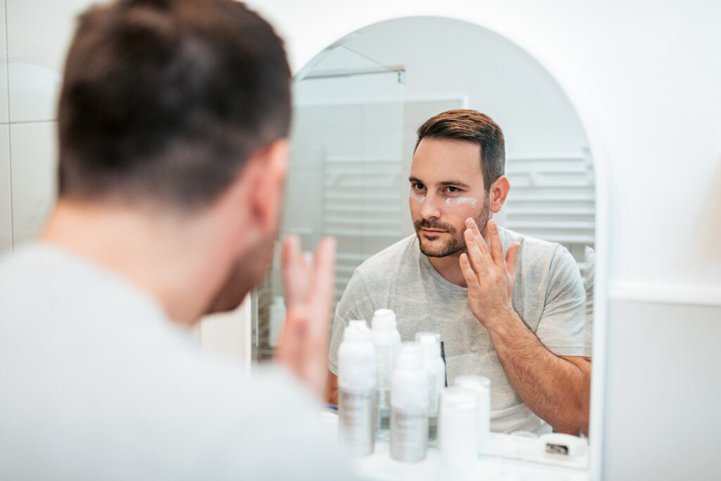iStock 1095554738 1024x683 - Handsome man applying face cream in the bathroom. -